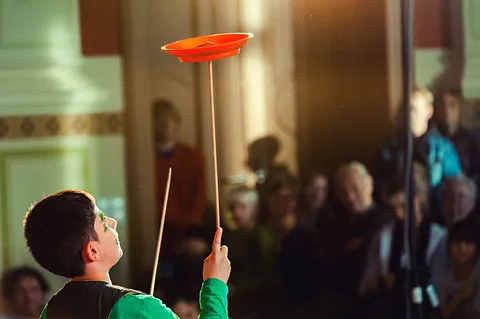 Junge vor Publikum beim Tellerdrehen